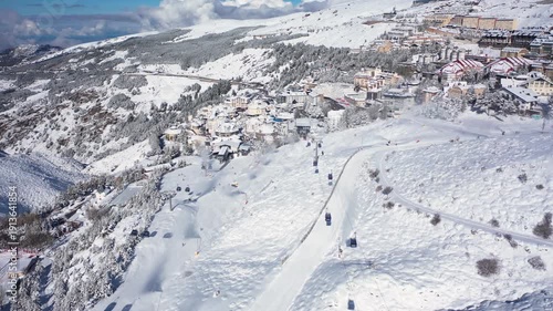 Aerial 4K video from a drone to Sierra Nevada ski resort on a sunny winter day in the mountains, Spain. Sierra Nevada is the largest mountain range near the city of Granada in Spain with snow. Sierra 