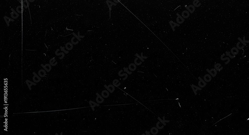 Abstract black background with subtle white scratches and dust particles.