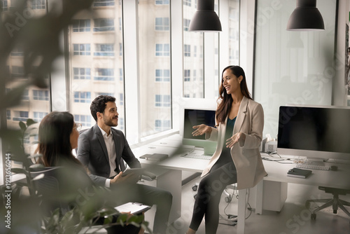 Team engaged in professional conversation during meeting takes place in modern coworking office, woman leading discussion or presenting idea to colleagues. Collaboration, communication, productivity