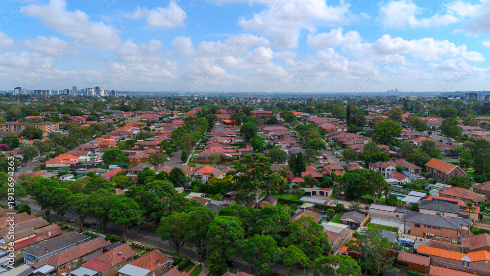 Obraz premium Panoramic Aerial Drone view of Inner Western Suburbs of Sydney housing, roof tops, the streets and the parks, the roads and trees of Ashbury Ashfield Burwood Summer Hill Canterbury and Campsie in Sydn