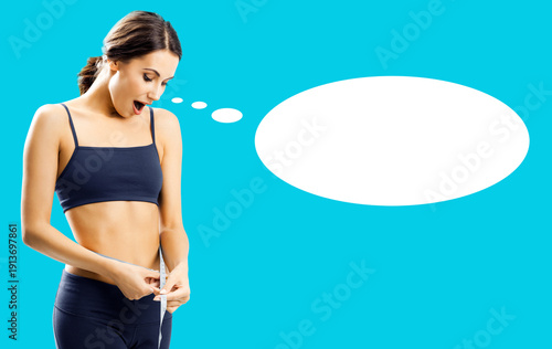 Shocked woman with wide open mouth wear black fitness wear hold tape measure. Happy surprised slim girl measure waist size, isolated blue green background. White empty speech bubble free ad text space