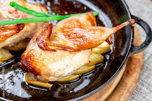 Fried Quail on Apples, Served in a Cast Iron Skillet. Close-up