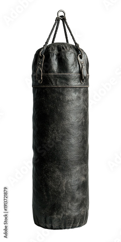 A worn, dark grey, cylindrical heavy punching bag hangs vertically against a stark black background