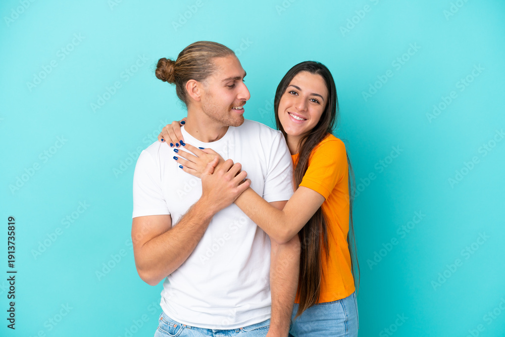 Fototapeta premium Young caucasian couple isolated on blue background laughing and hugging