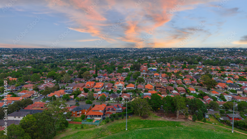 Obraz premium Panoramic Aerial Drone view of Inner Western Suburbs of Sydney housing, roof tops, the streets and the parks, the roads and trees of Ashbury Ashfield Burwood Summer Hill Canterbury and Campsie in Sydn