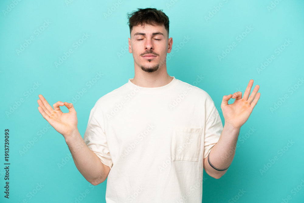 Fototapeta premium Young caucasian handsome man isolated on blue background in zen pose