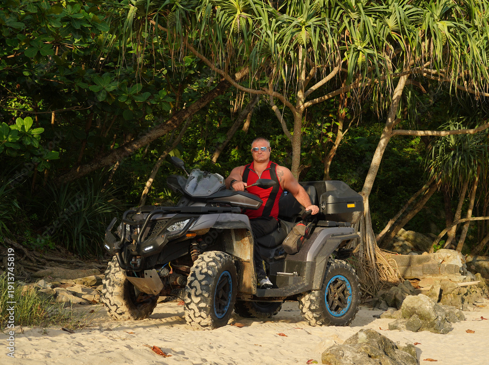 Fototapeta premium A man engages in extreme ATV riding on sand beach early in the morning