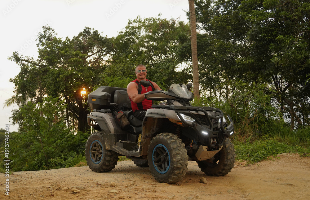 Fototapeta premium A man engages in extreme ATV riding on mountains in the evening