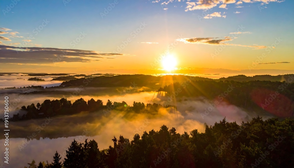 Obraz premium Aerial view of a radiant sunrise over forested hills and a misty valley, with a lake reflecting the golden light