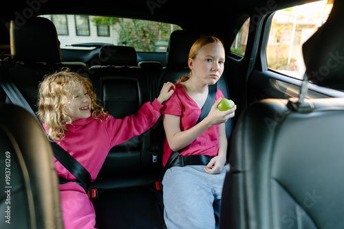 Tableau sur toile Two sisters with different emotions sitting in car, sibling relationship and fam
