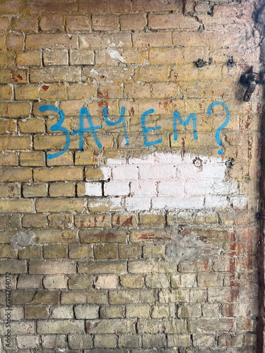 Weathered brick wall featuring a bold blue painted question in Cyrillic, Kyiv Ukraine