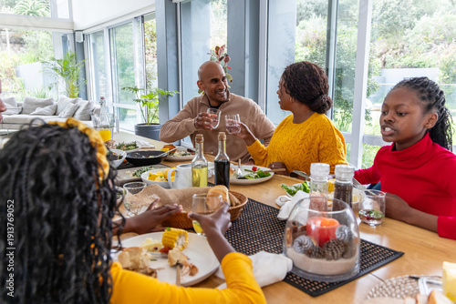 African American family sharing meal in sweaters at dining table with orange juice