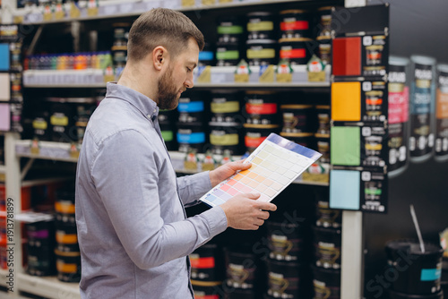 Obraz na plátně Man shopping for paint in a hardware store selecting color swatches for home ren