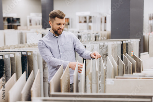 Photography Man choosing ceramic flooring tiles in a showroom, planning interior design for