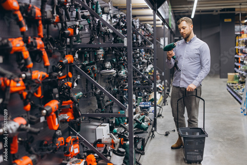 Man choosing a new power tool in hardware store, browsing selection for DIY projects and home renovation