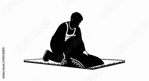 Person on knees rolling up a turf carpet on grassy surface