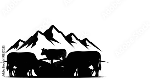Silhouetted cows graze in front of jagged mountain peaks