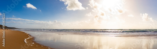 Canvas Print The mirror-like surface of the sand on the ocean shore, reflecting the clouds