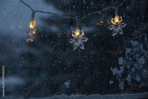 decorative snowflake light string on frosty window