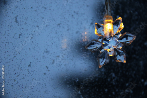 decorative snowflake light string on frosty window