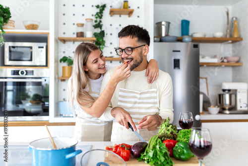 Billede på lærred Happy Young Couple Tasting Food while Cooking