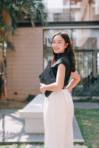 Fotografie Smiling Asian woman holding digital tablet outdoor