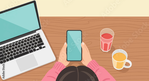 Person holding smartphone near laptop and drinks on wooden table