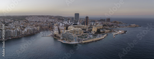 Aerial view of the urban landscape with its modern architecture meeting the tranquil sea, a blend of beige buildings and blue waters, St. Julian's, Sliema, Malta.
