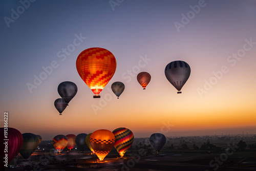 varios globos o balones aerostáticos volando por el cielo de Luxor en Egipto al amanecer en la hora azul
