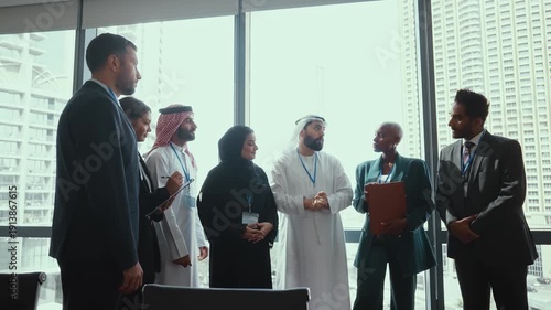 Western and emirati businesspeople in traditional arab attire participating in a conference with ceo, collaborating and taking notes in modern office environment