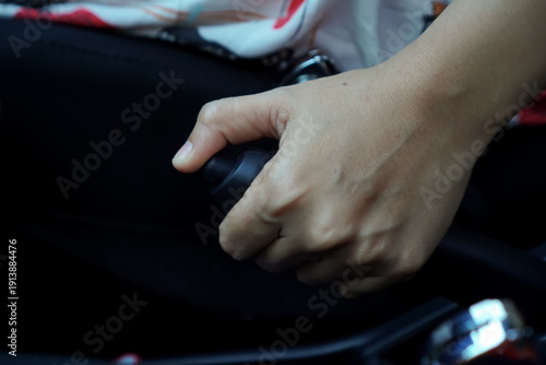 Close-up of the hand of a woman operating the parking brake lever inside a vehicle