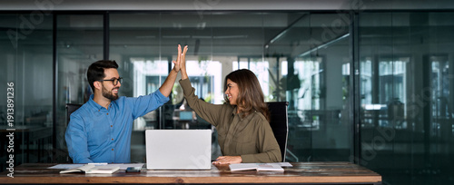 Happy successful business team of two executive partners employees giving high five supporting celebrating professional success growth financial work achievement sitting at office meeting with laptop.