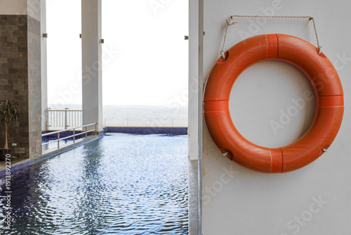 Bright Orange Rescue Lifebuoy Mounted on a Wall by a Swimming Pool
