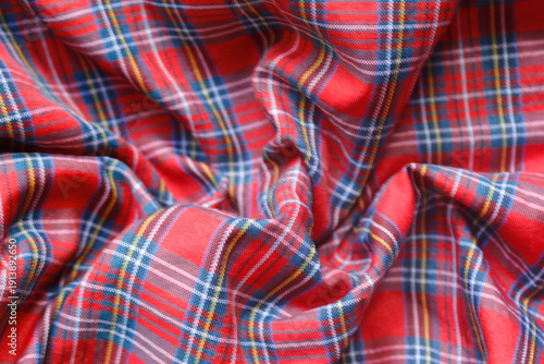 Red plaid fabric with blue, white, and yellow accents. Ideal for cozy home decor, crafts, quilts, and textile projects, evoking warmth, tradition, and rustic charm.