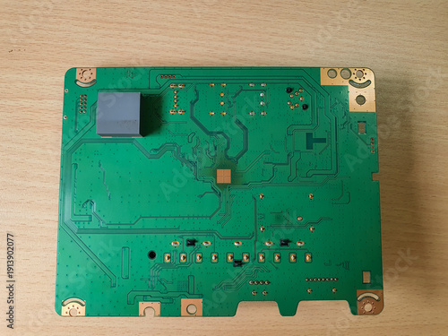 Back side of a green printed circuit board with electronic components.