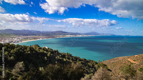 Foto Panoramic view of M’diq bay, wide beach, coastal town, mountains in the background and turquoise sea beneath a bright cloudy sky