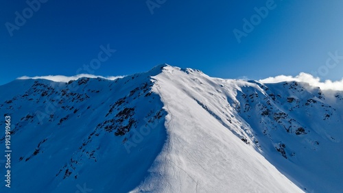 Where the sky meets the snow
At the summit, the horizon stretches endlessly, blending icy terrain with a pale winter sky. The snow reflects soft light, creating a scene that feels both harsh and peac