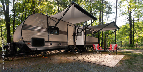 Shady spot in a forested campsite with awnings out on a travel trailer