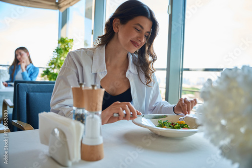 Quadro em tela Dark-haired smiling woman having her meal at the restaurant