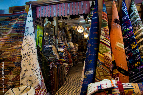 Moroccan carpet shop entrance at night with stacked traditional rugs inside
