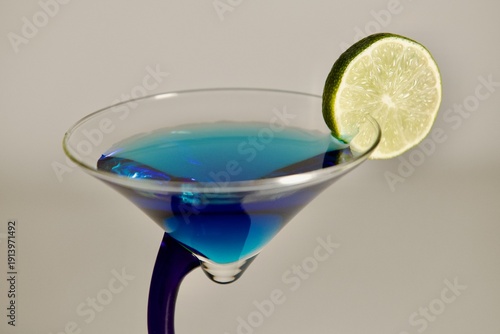 blue cocktail with lime in a blue martini glass