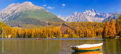 Štrbské Pleso (Strbske Pleso) in the High Tatras, Slovakia, with a panoramic view of a mountain lake surrounded by vibrant autumn foliage. Crystal clear water, dramatic sky, and majestic alpine peaks 