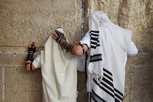 A jewish boy and his father pray at the Western Wall
