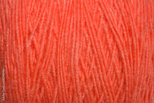 A detailed close up view shows the soft and fuzzy texture of orange wool yarn wound tightly together