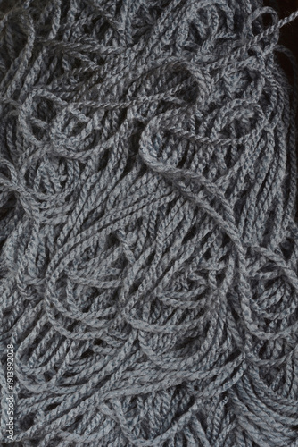 A macro close up shot of dark grey knitting wool yarn showing a complex tangled fiber texture