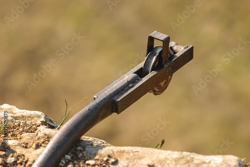 Old rusted iron guide pulley mounted on a rock. Vintage industrial remnant of a quarry winch or mining cable system found in nature.
