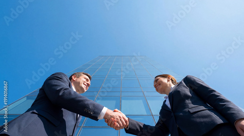 Low Angle View of Business Handshake Against Blue Sky and Skyscraper