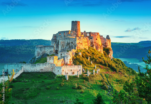 Spiš Castle (Spišský hrad) in Slovakia, a historic stone fortress perched on a hilltop, with panoramic views of the surrounding mountains. Dramatic sky, vibrant colors, and natural light highlight the