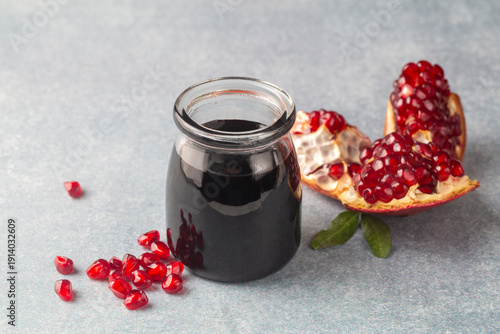Billede på lærred Glass bottle of pomegranate sour sauce with fresh ripe whole and split pomegrana