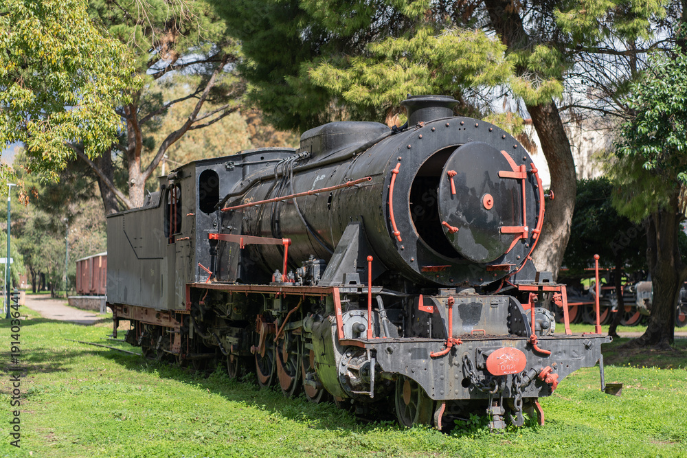 Obraz premium Well-preserved historic locomotive photographed outdoors in Greece under clear daylight.